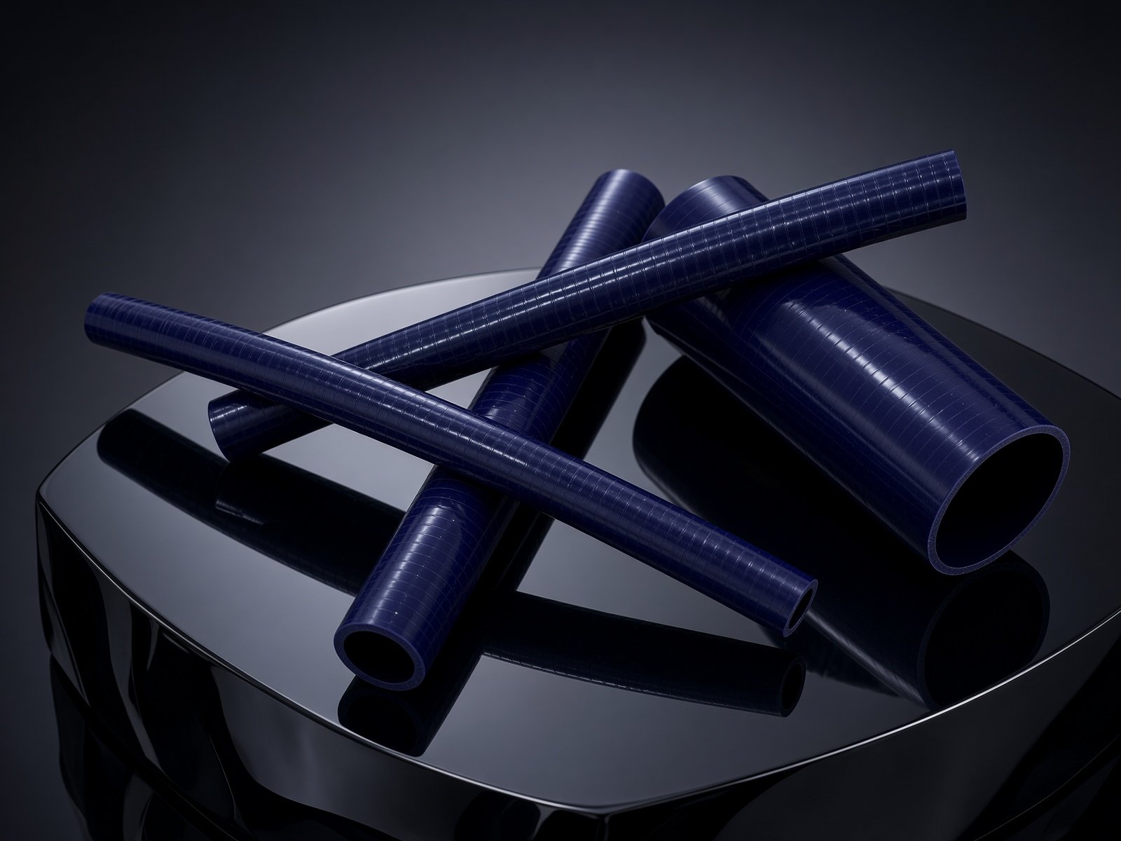 OATMaster blue-violet silicone coolant hoses crossed on a glossy black pedestal